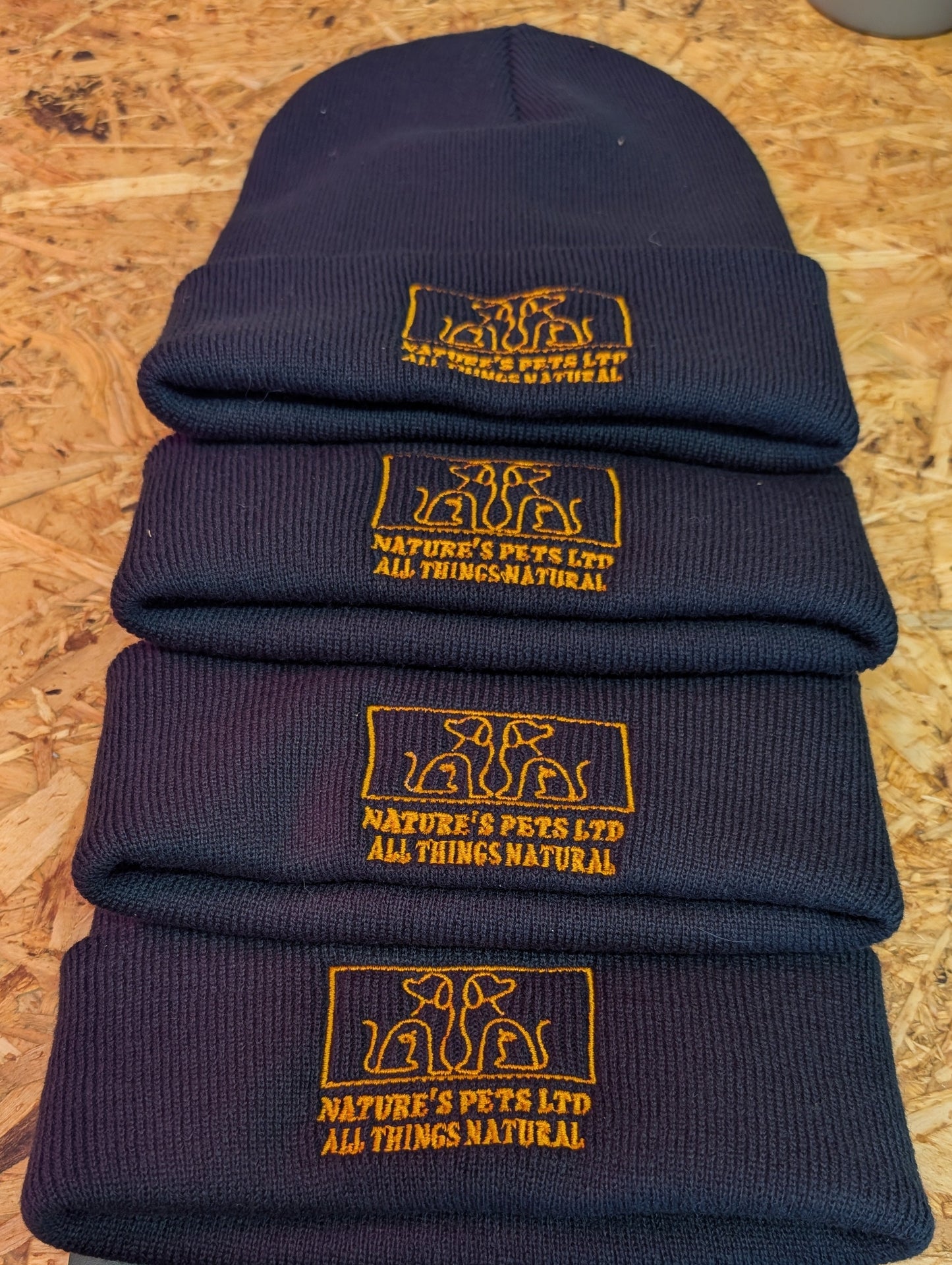 Stack of Nature's Pets branded winter hats for dog walkers